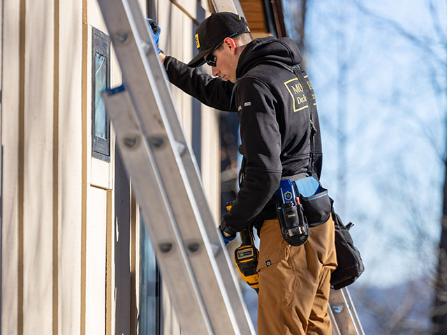 Mountain Deck and Exteriors Brevard North Carolina Construction Worker on Ladder Against Wall
